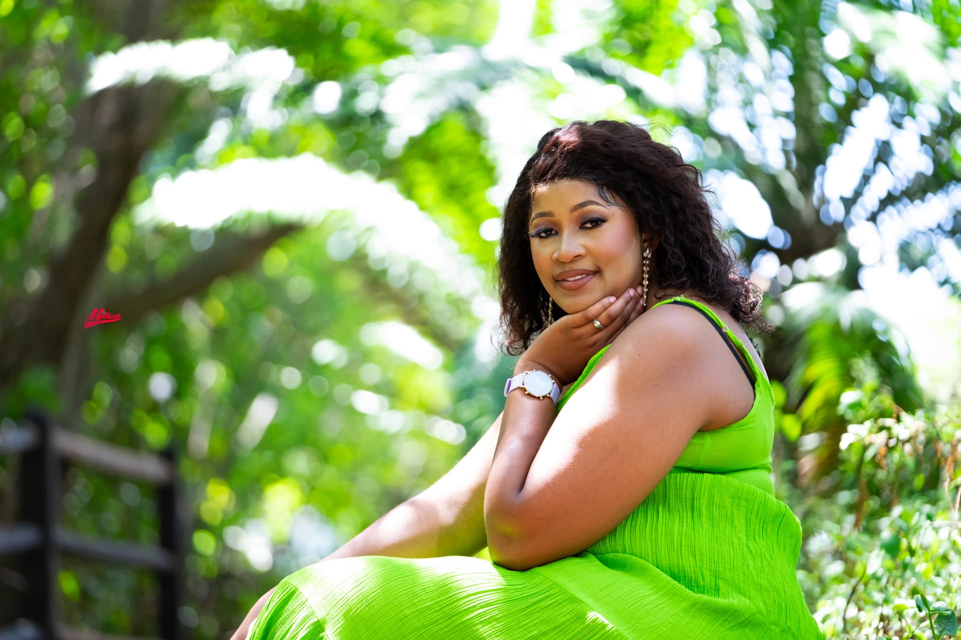 Outdoor portrait of a woman in a green dress against soft greenery