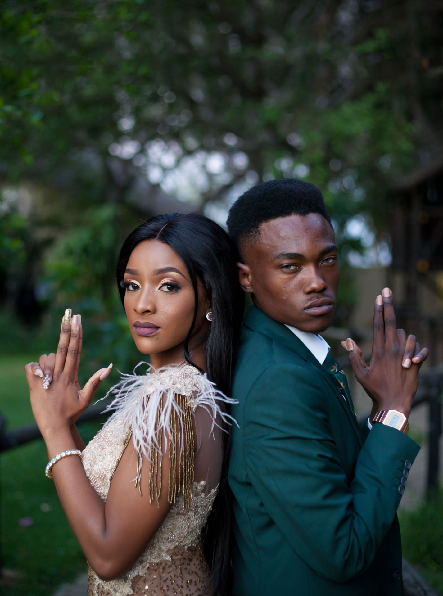 Couple posed back to back under trees, shot with shallow depth of field